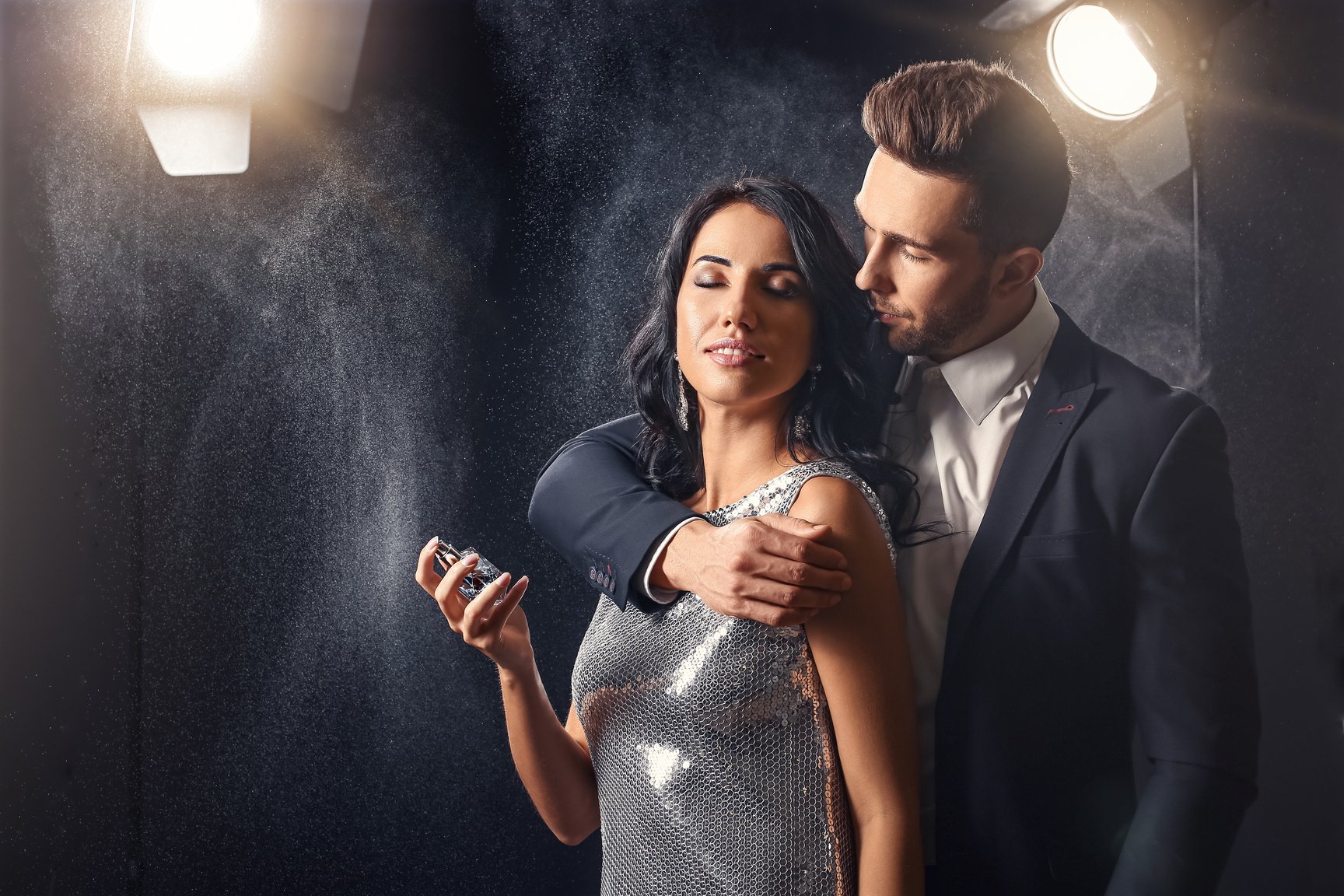 Stylish Young Couple with Perfume on Black Background